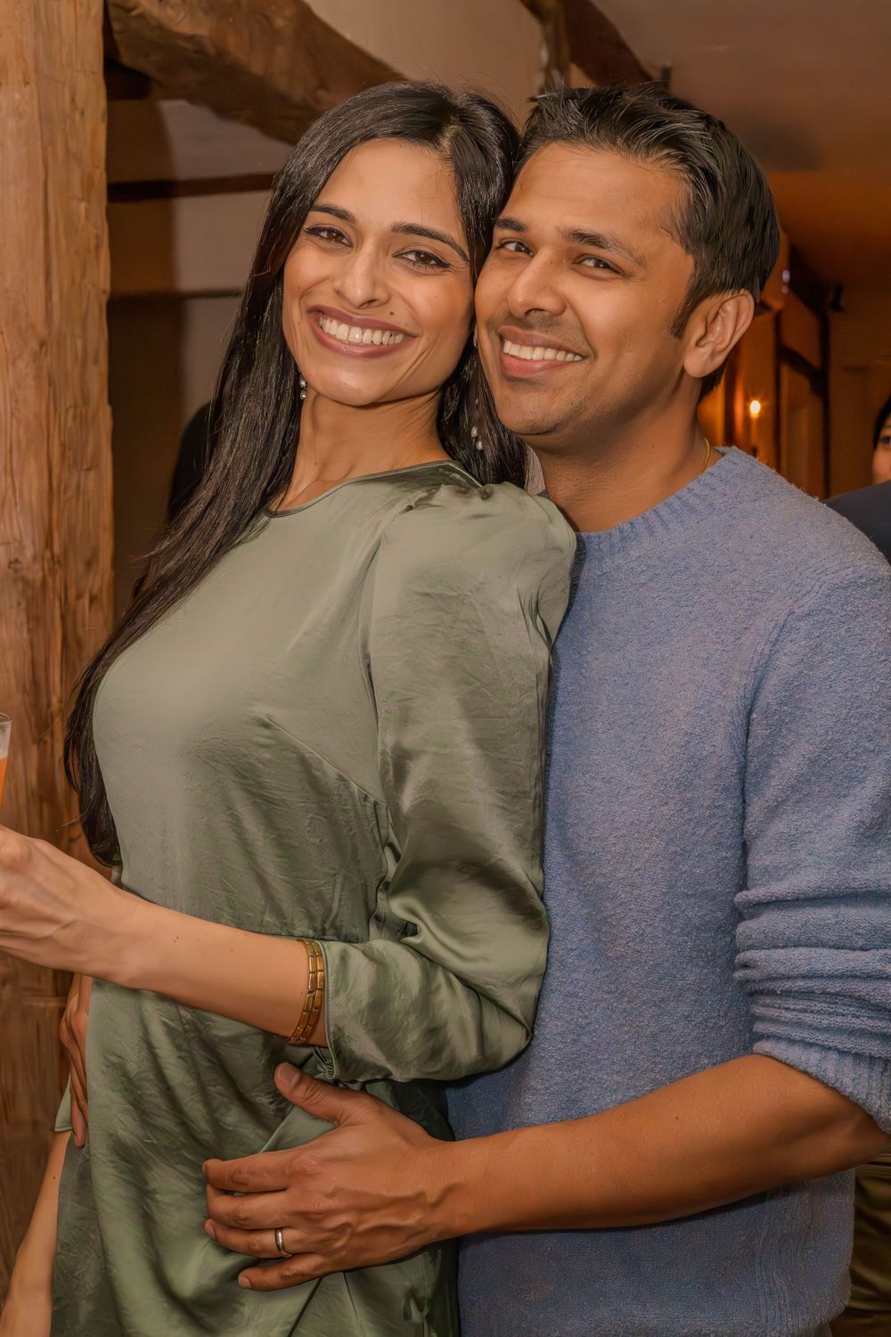 Couple sharing an intimate moment while embracing in a warmly lit indoor setting.
