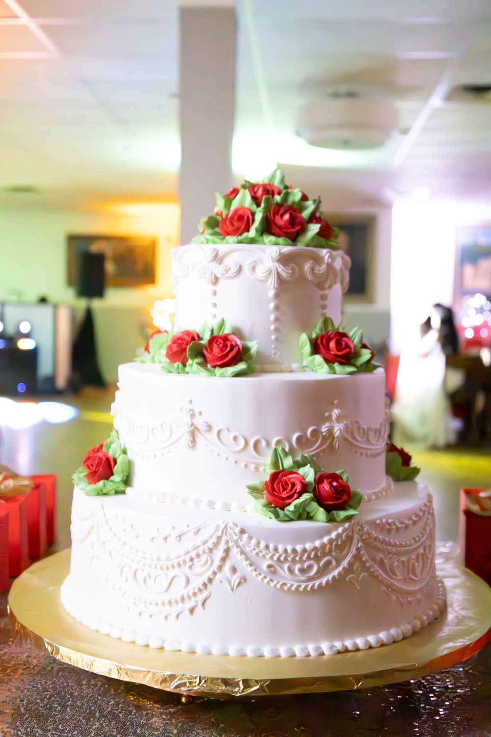 Elegant white wedding cake decorated with delicate piping and red sugar roses.