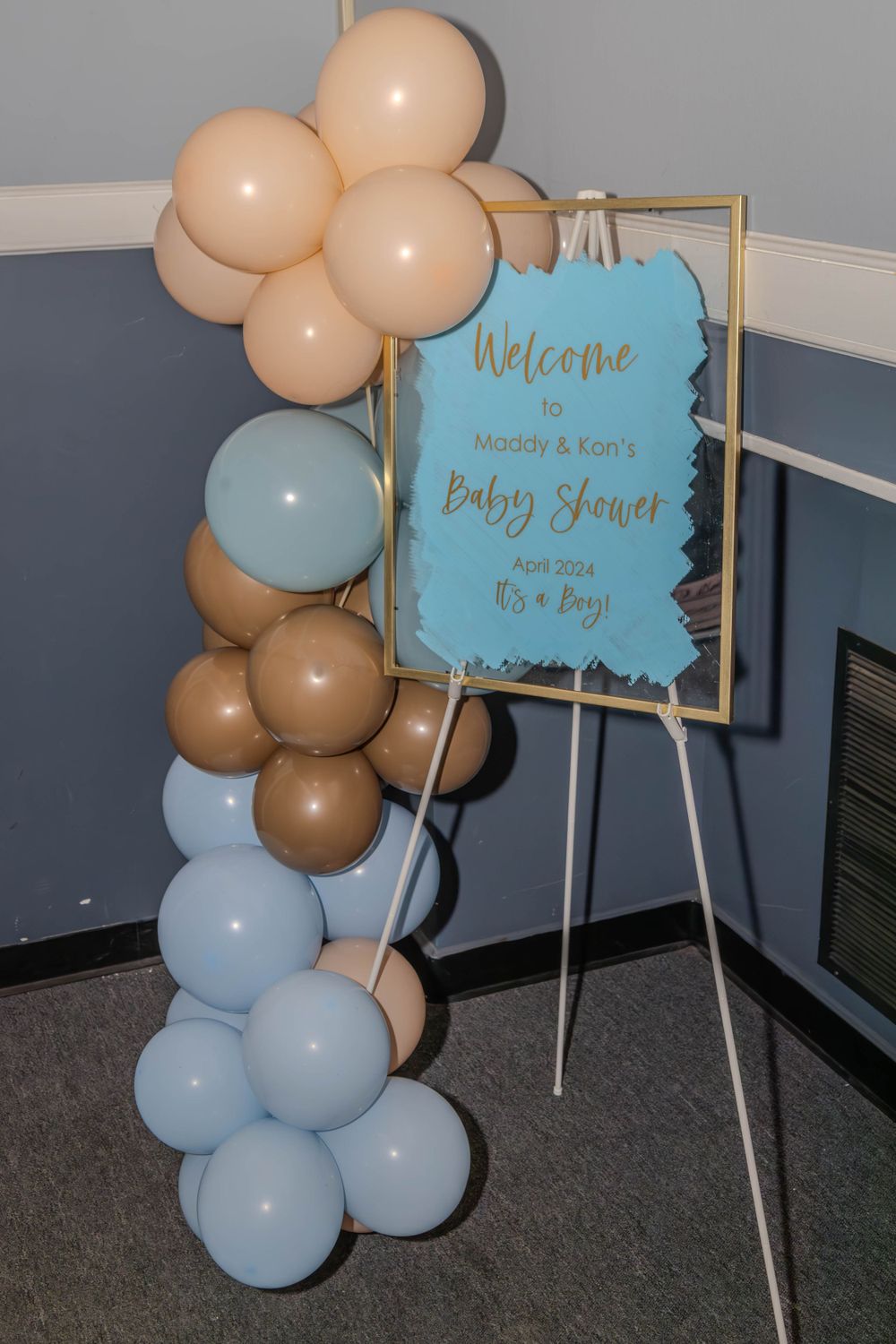 Baby shower welcome signs and balloon arch in soft blue and beige colors.