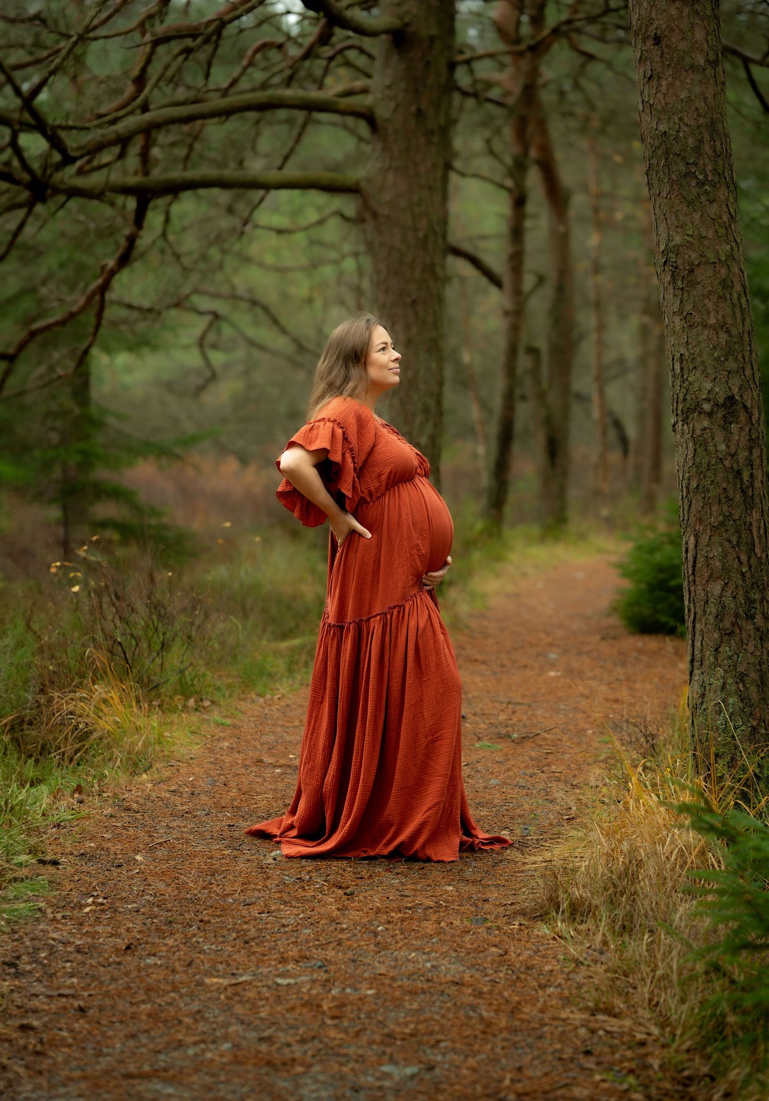 Gravid kvinne i rød kjole i skog