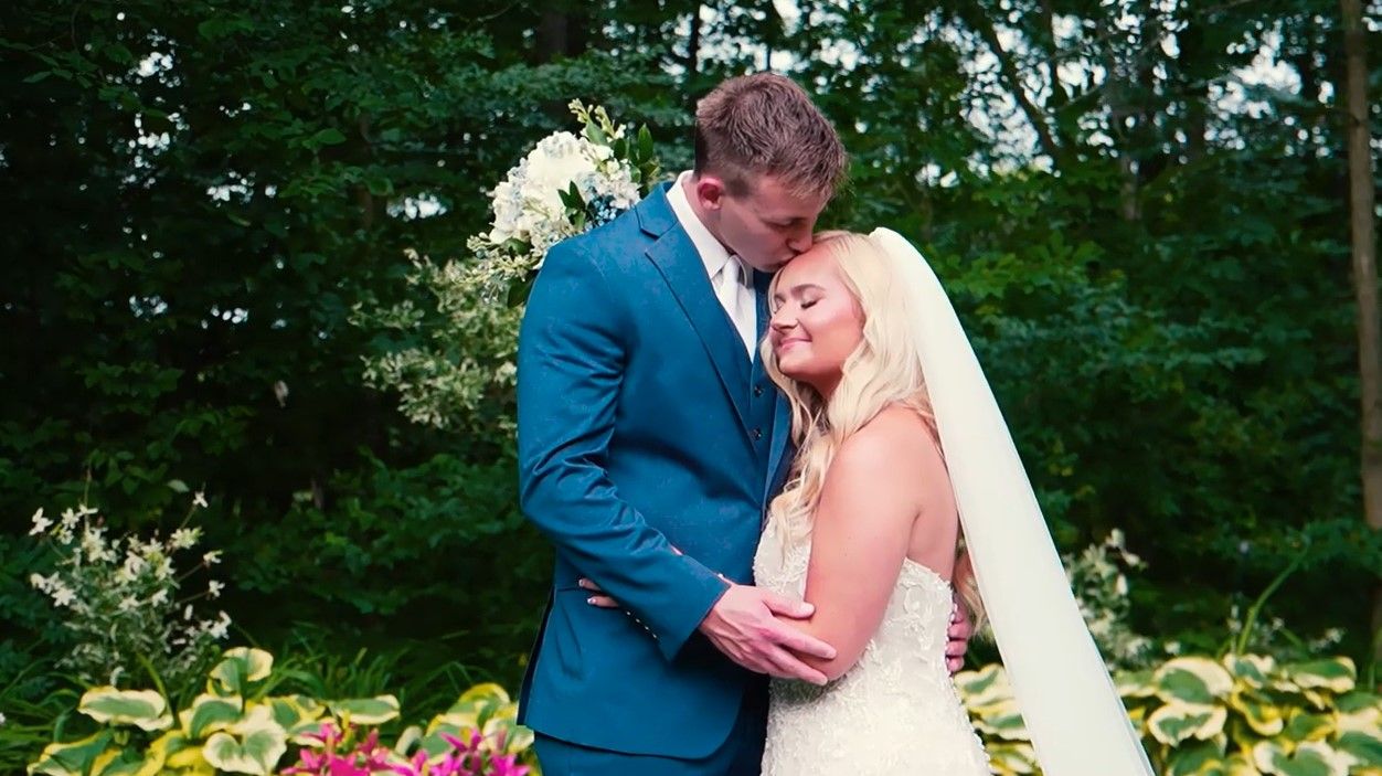 Intimate wedding portrait of couple embracing in garden with white floral bouquet.