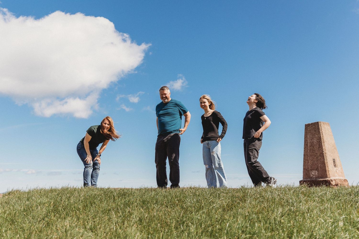 People standing on a hilltop against a blue sky with white clouds.