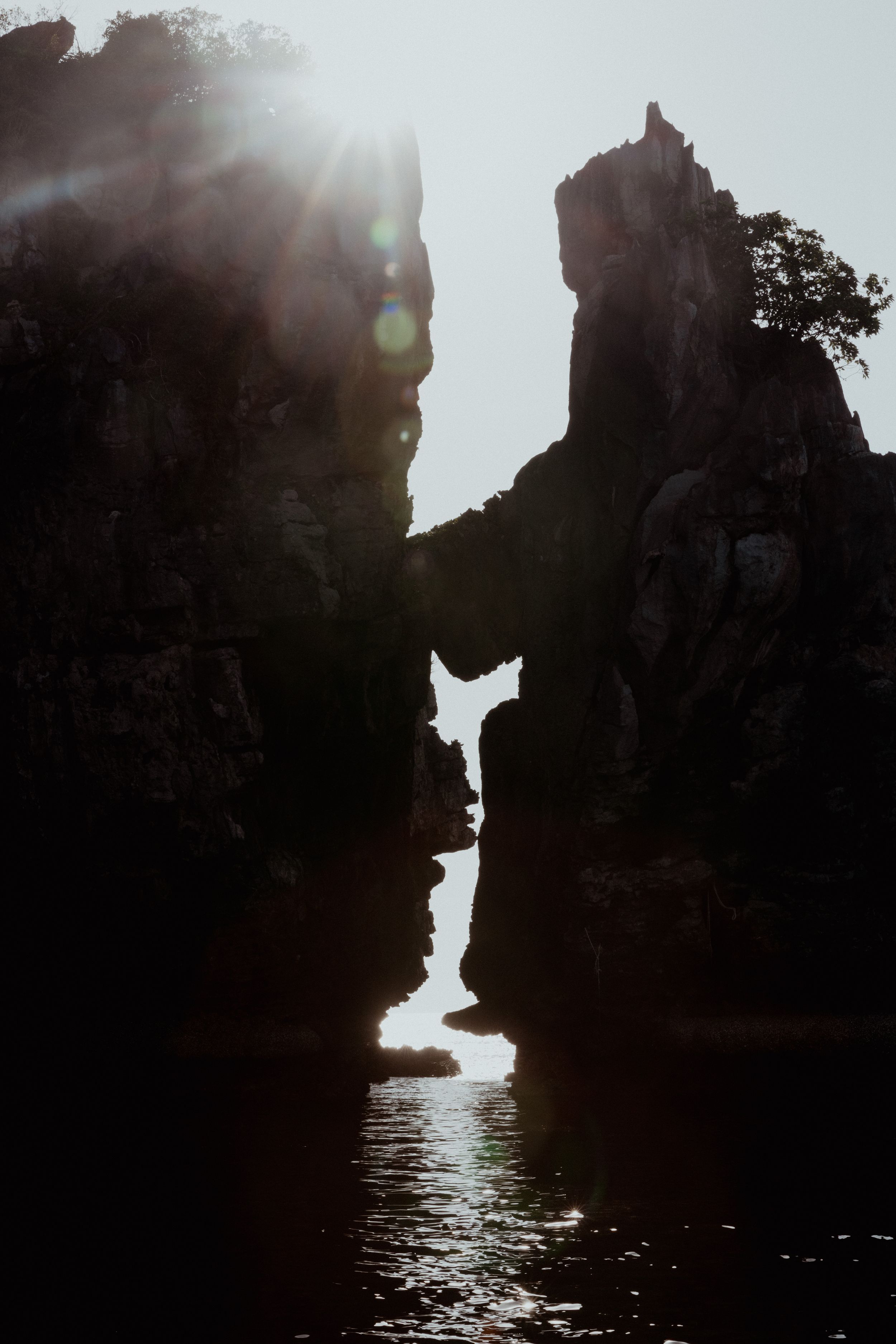 Dramatic silhouette of rock formations creating a narrow ocean channel at sunset.