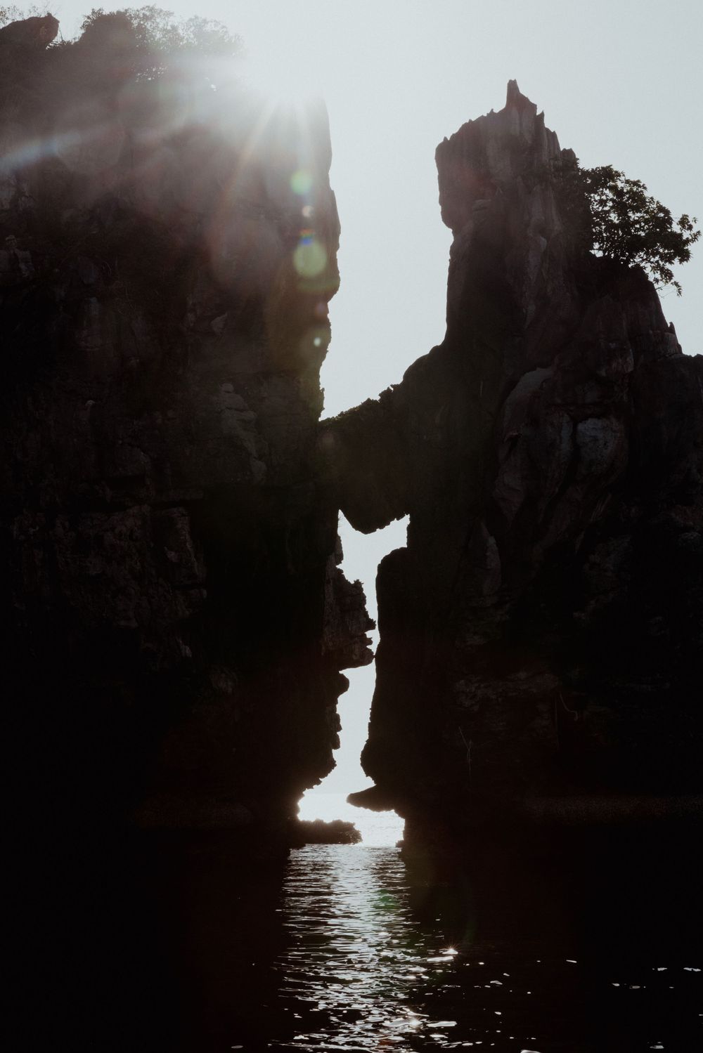 Dramatic silhouette of rock formations creating a narrow ocean channel at sunset.