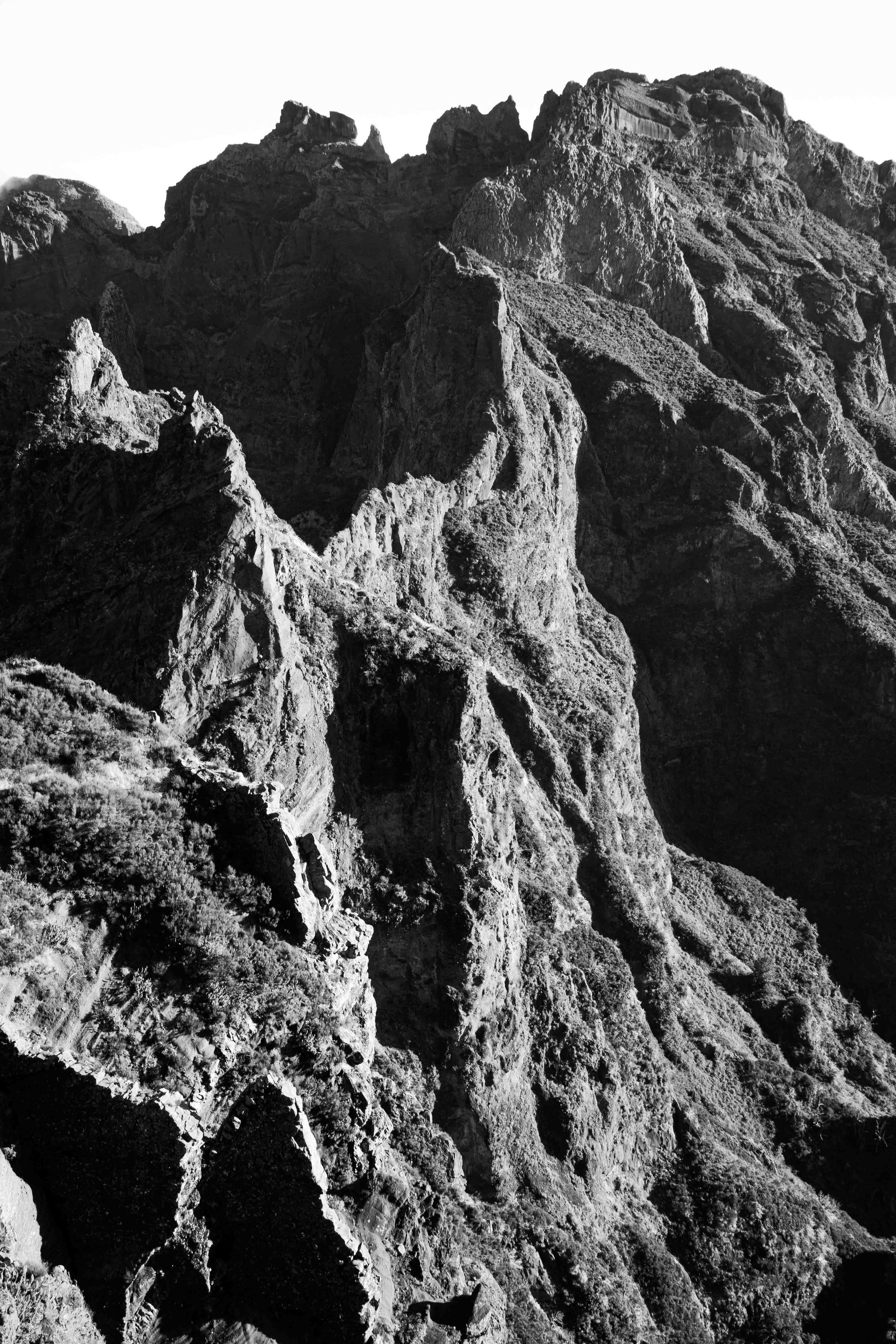 Dramatic black and white photograph of jagged mountain peaks and rocky cliff formations.
