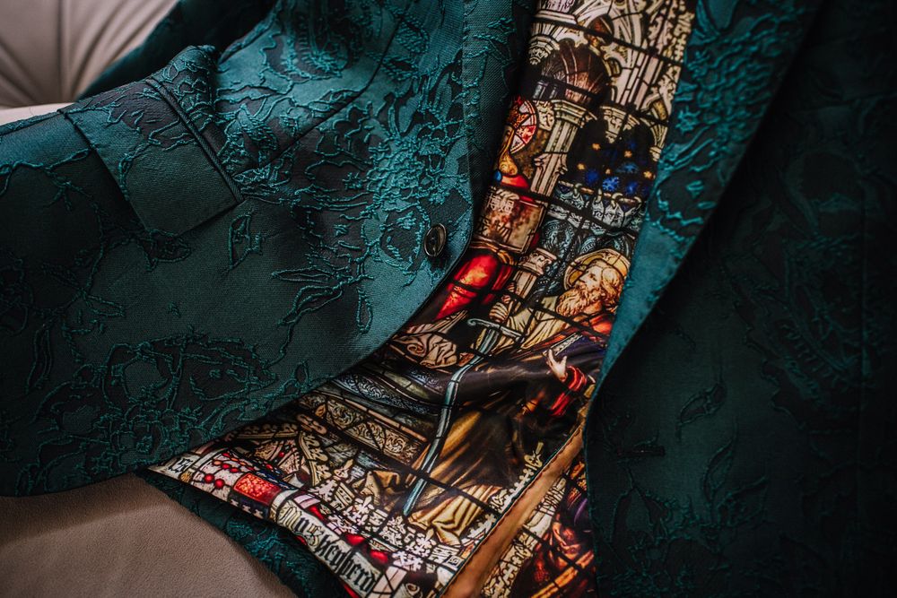 Teal damask jacket with stained glass window lining featuring colorful religious figures.
