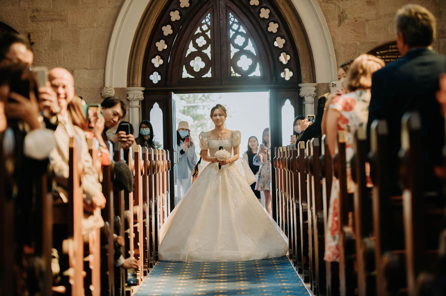 Bride walking down church aisle with guests lining pews.