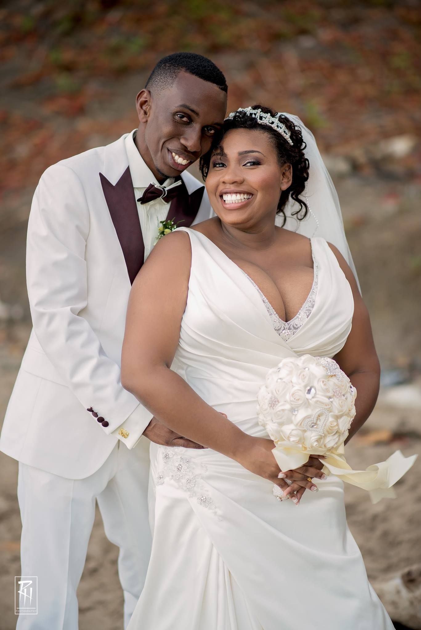 Wedding portrait featuring couple in white formal attire with crystal bouquet against natural backdrop.