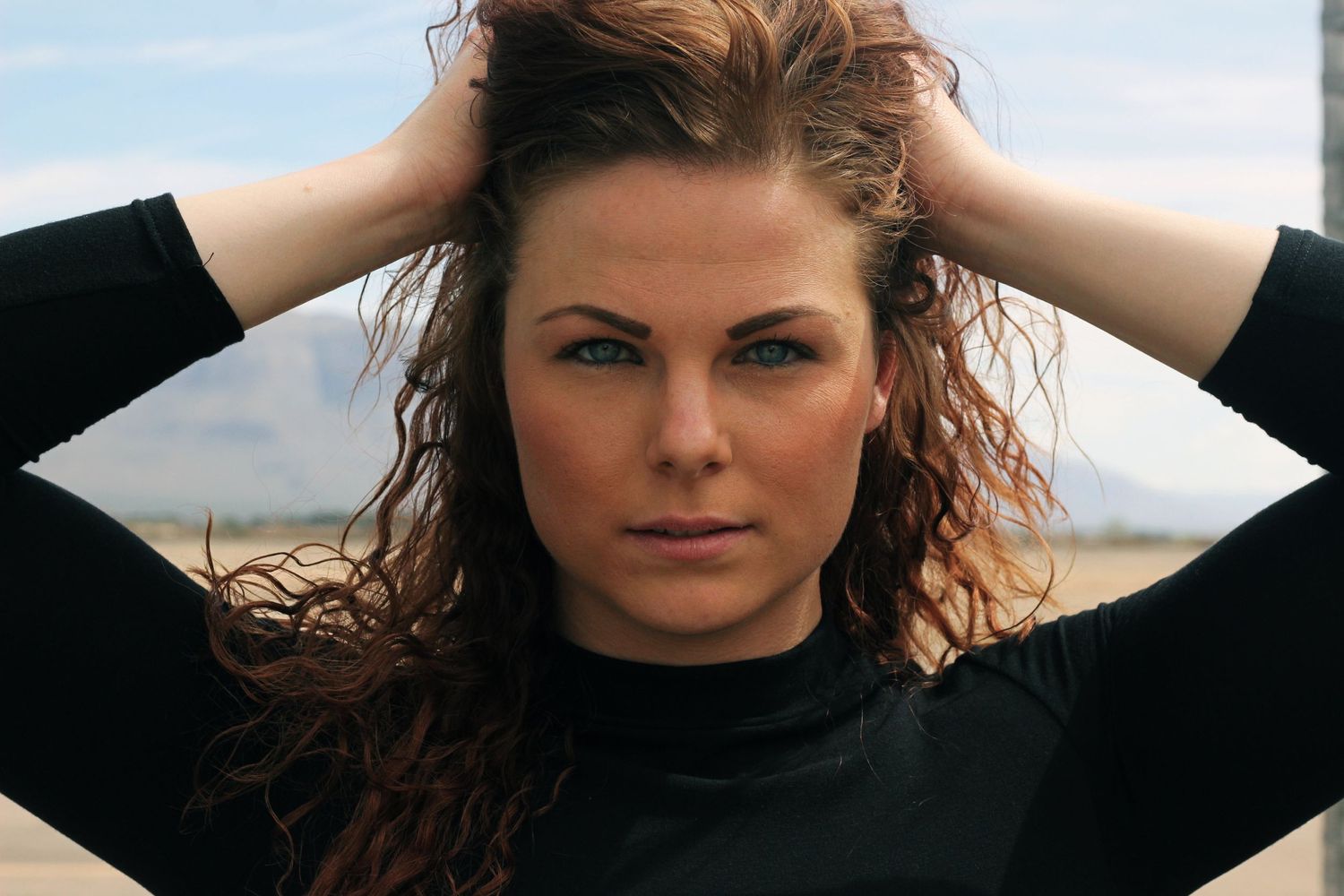 Outdoor portrait with windswept hair against natural lighting.