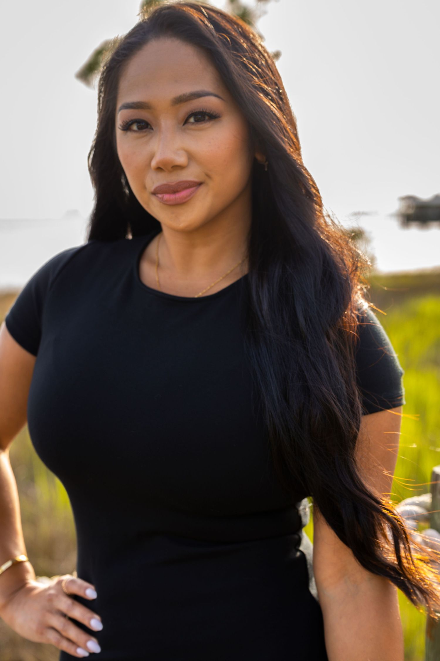 Woman in black t-shirt poses for casual outdoor portrait series in natural lighting.