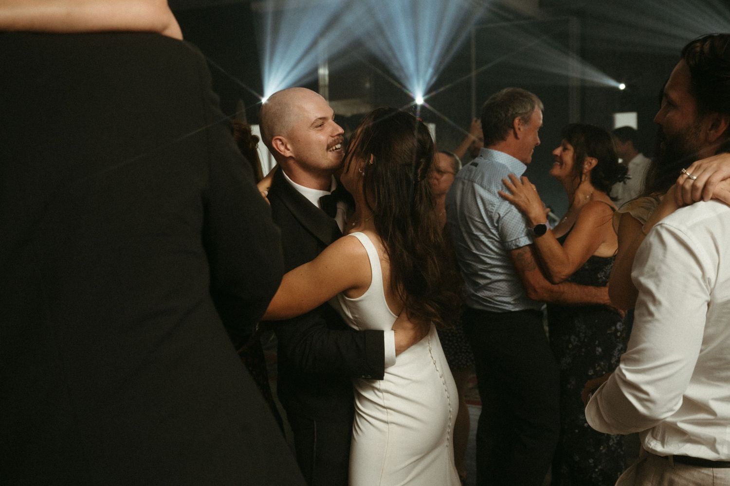 A romantic sparkler-lit wedding celebration moment with bride and groom embracing under glowing sparklers at night.