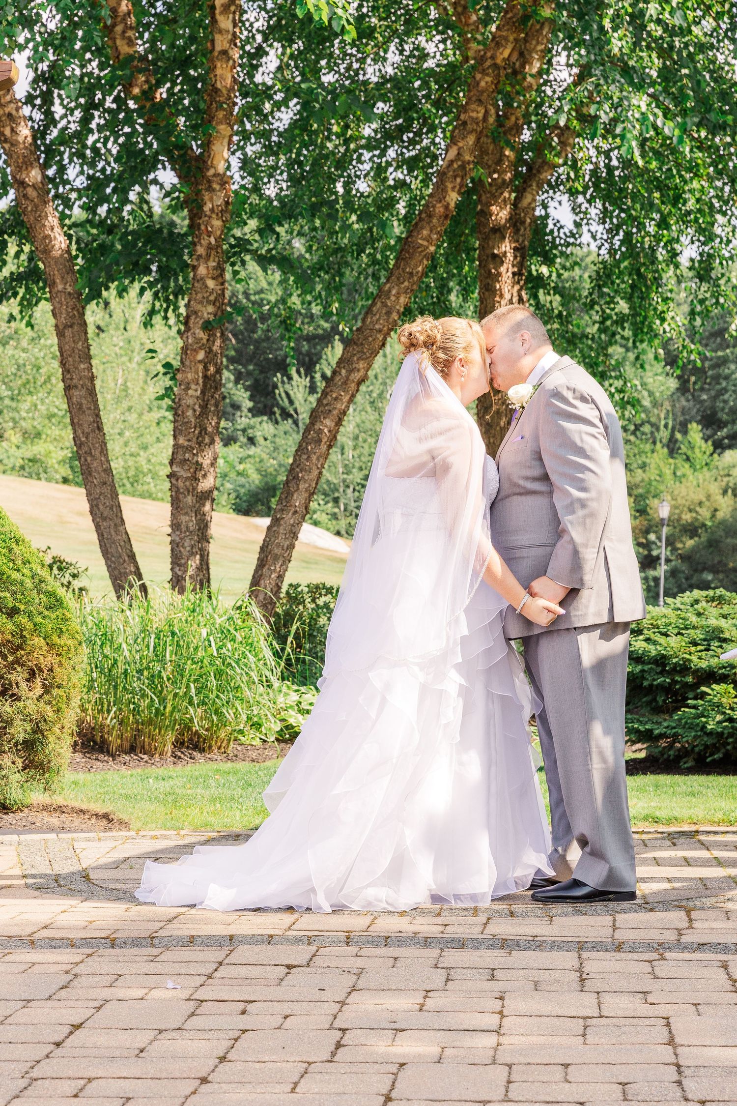 Couple sharing intimate moment on brick patio under birch trees.