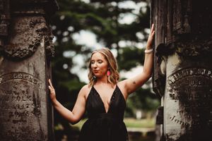 Dramatic portrait at historic stone archway with elegant black dress.