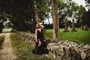 Elegant scene by stone wall with historic cemetery and path in background.