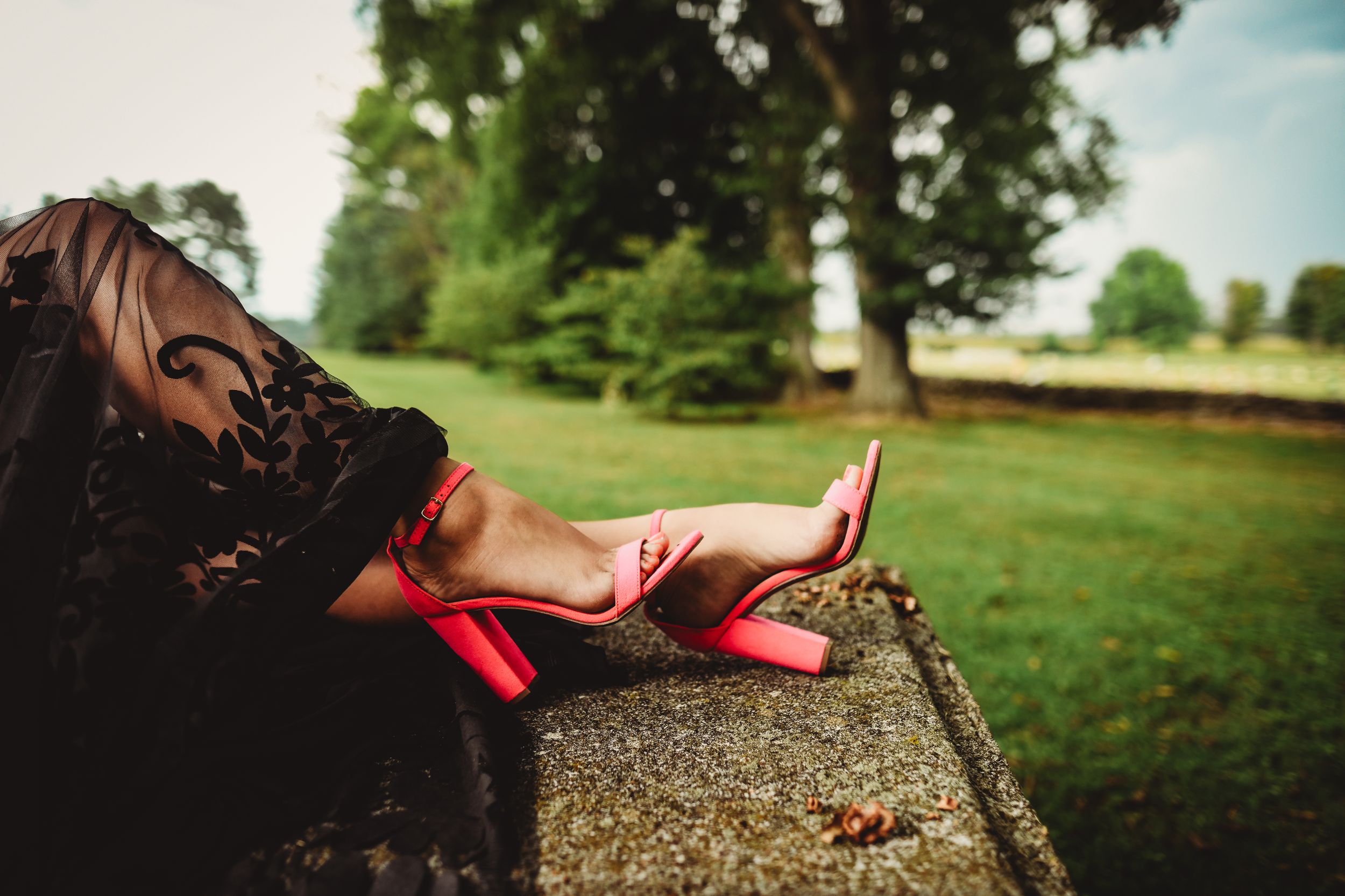 Artistic cemetery portrait showcasing black lace dress details against stone monuments.