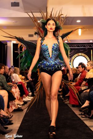 Stunning blue sequined bodysuit adorned with feathers and nature-inspired details on fashion catwalk.
