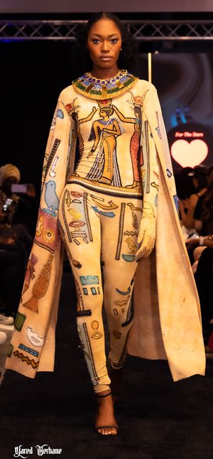 Egyptian-themed outfit featuring hieroglyphic prints and pharaoh motifs displayed on fashion runway.