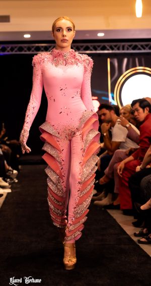 Model wearing fitted pink bodysuit with crystallized details and ruffled leg embellishments.
