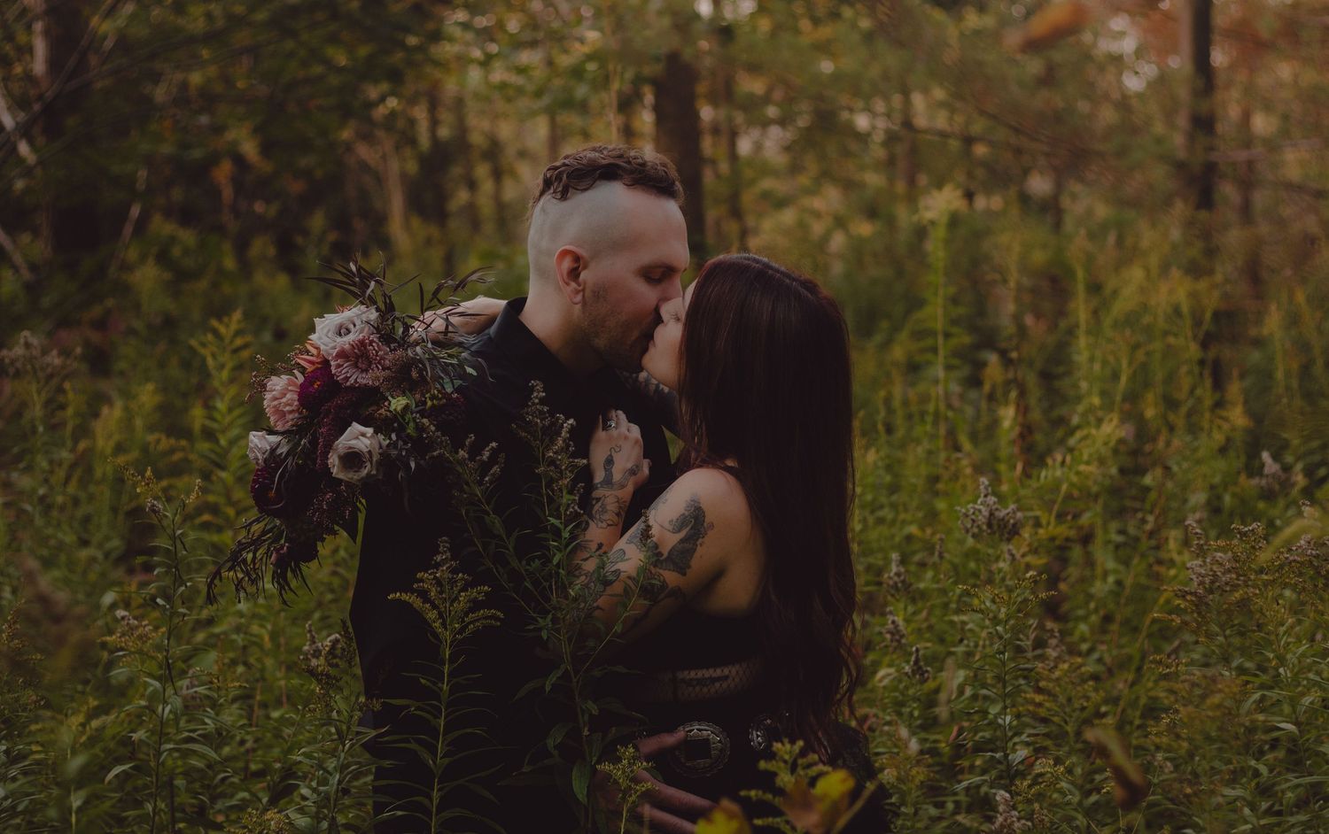 Intimate shot of elopement couple in the woods. Bride and groom are wearing all black.