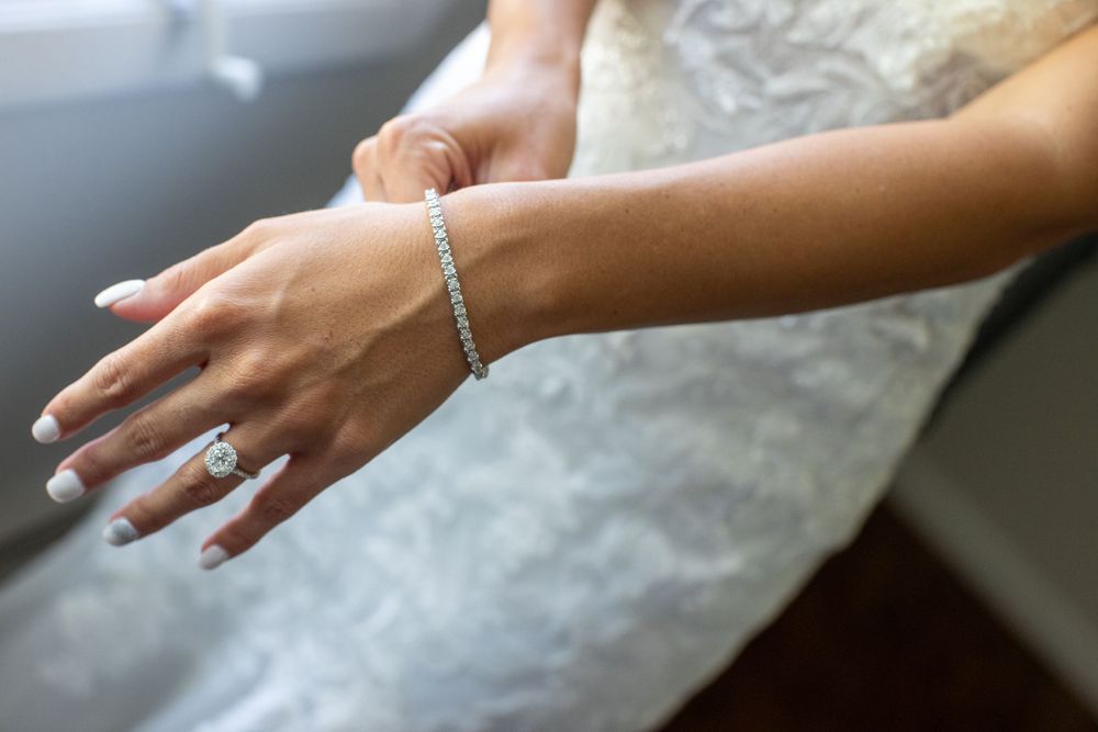 Close-up of bride's hands showing diamond engagement ring and tennis bracelet on wedding day.