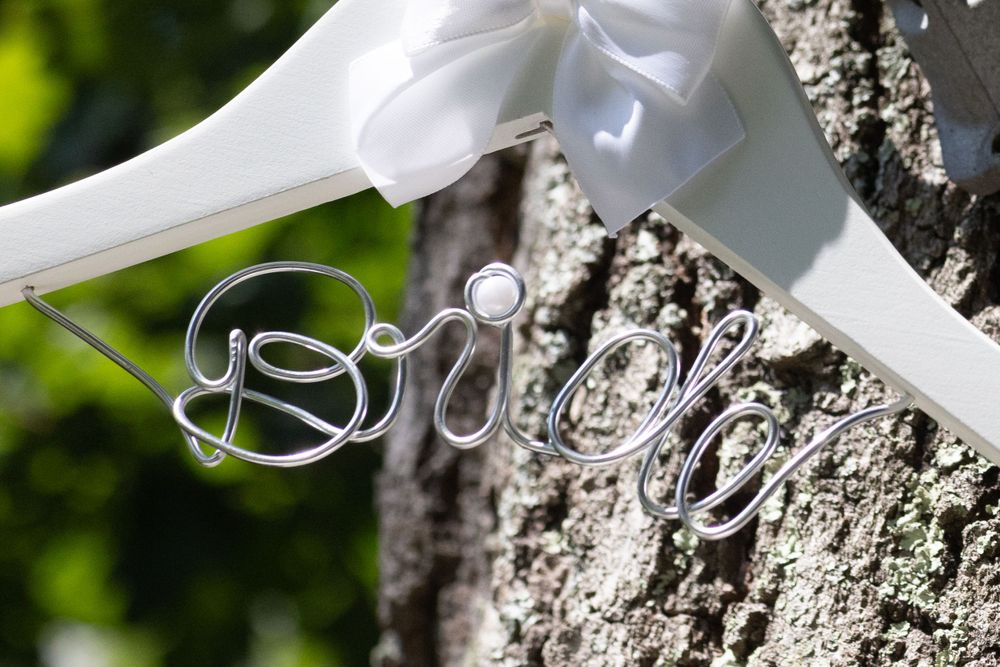Decorative wire Bride hanger hanging on tree bark with white ribbon bow for wedding day.