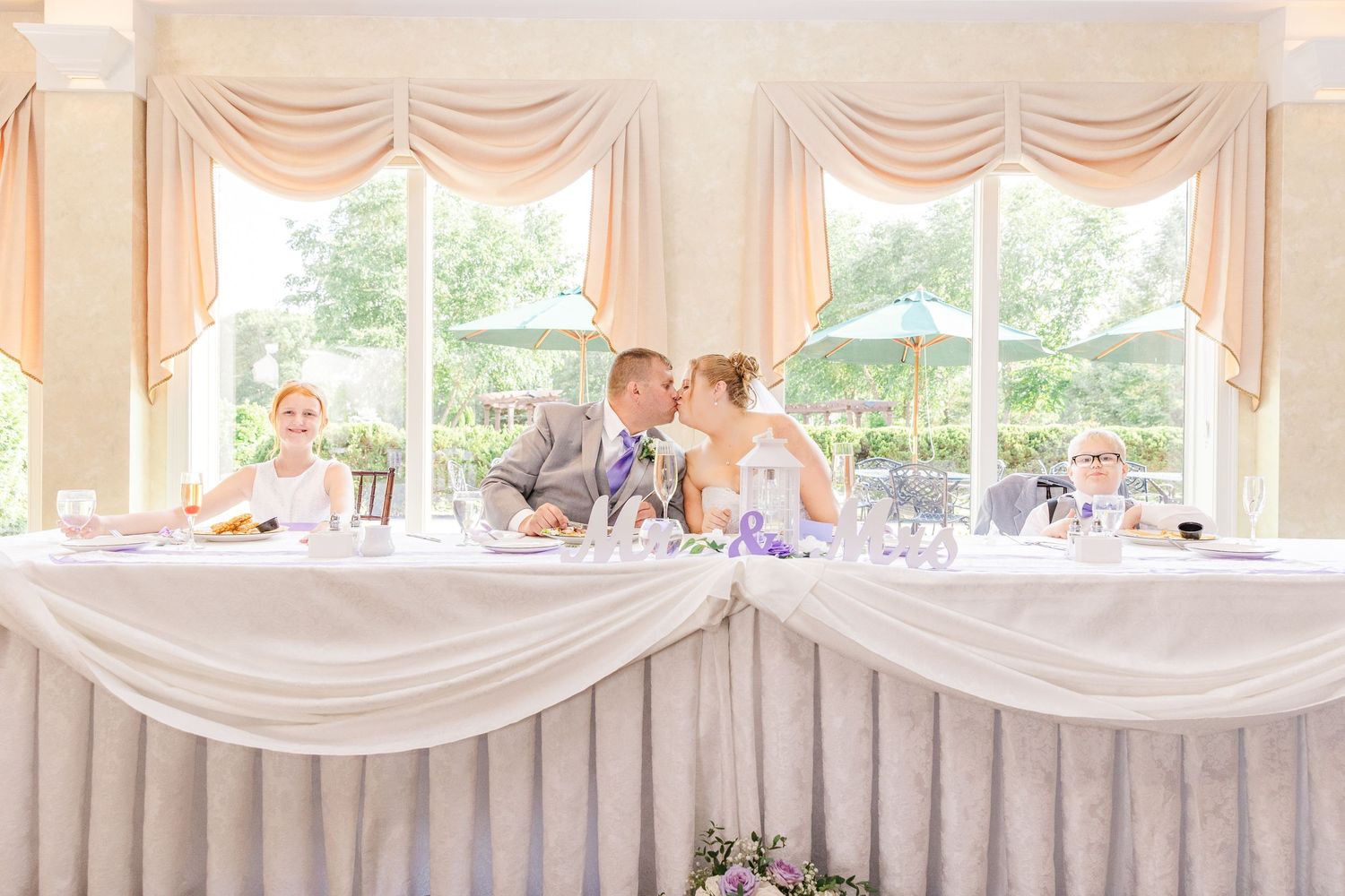 Newlyweds share an intimate moment at their decorated head table during the reception.