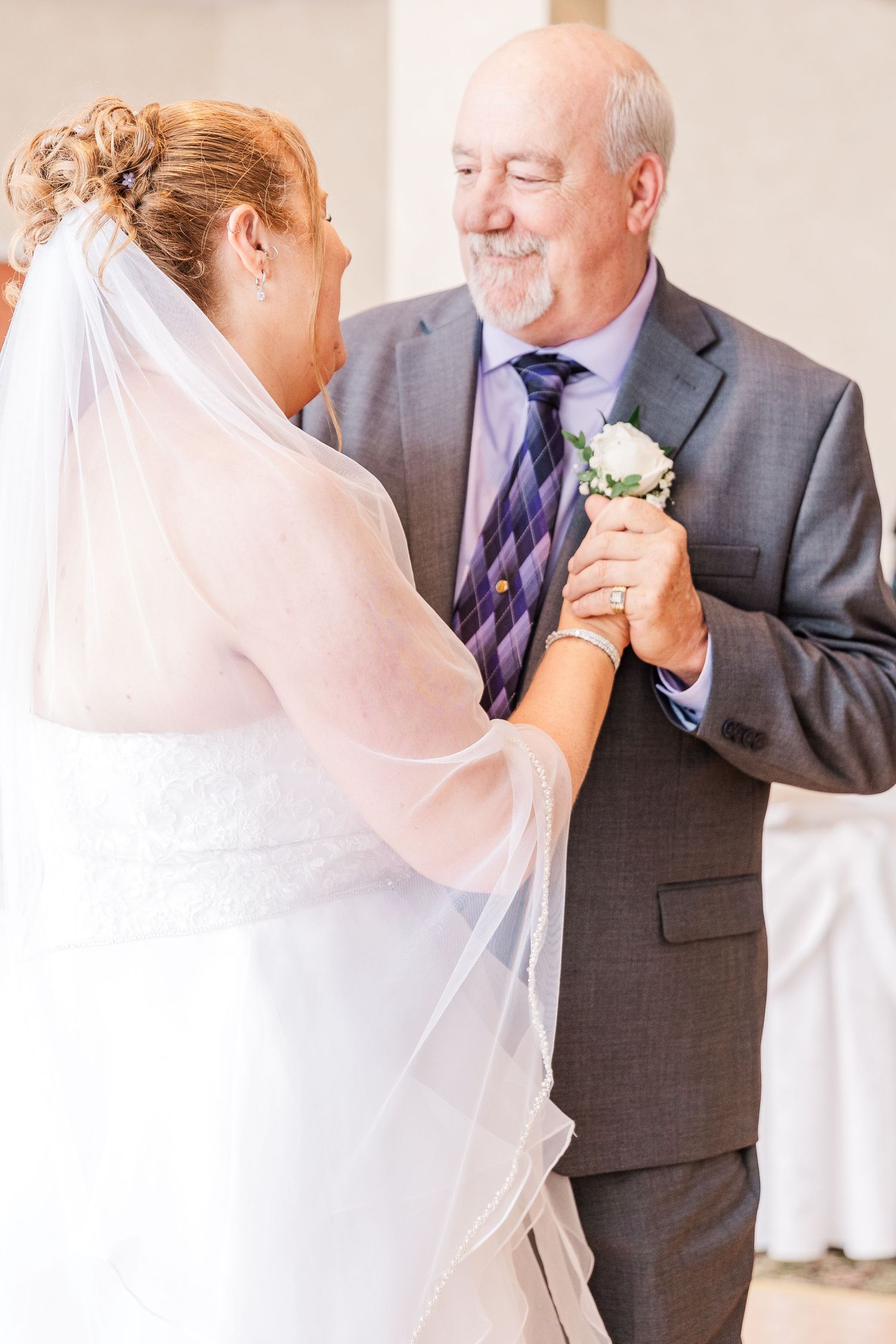 A tender dance moment at a wedding with the bride in white and a gentleman in a grey suit.