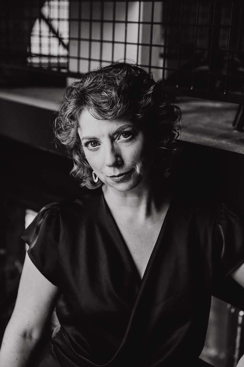 Zakelijke zwart-wit portretfoto van vrouwelijke ondernemer met natuurlijke uitstraling.
