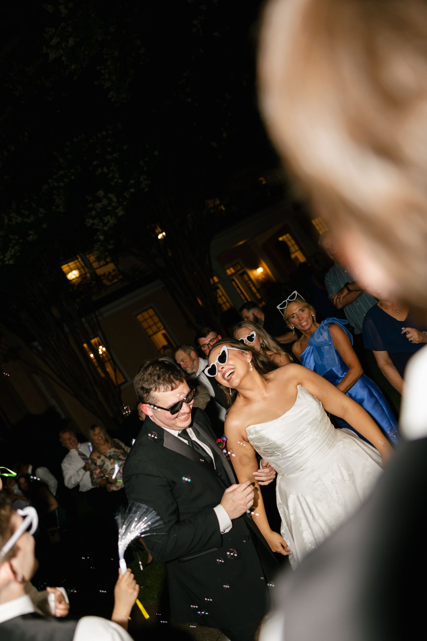 Couple dancing together at a lively wedding reception with guests in the background in Florence, AL.