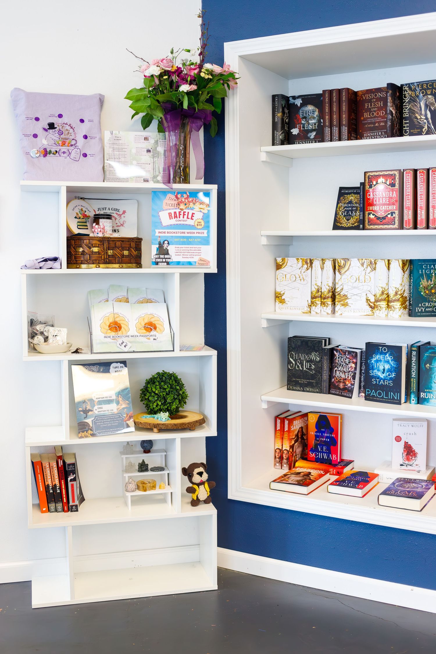 Modern bookstore display with white floating shelves against navy blue wall showcasing colorful book collections.