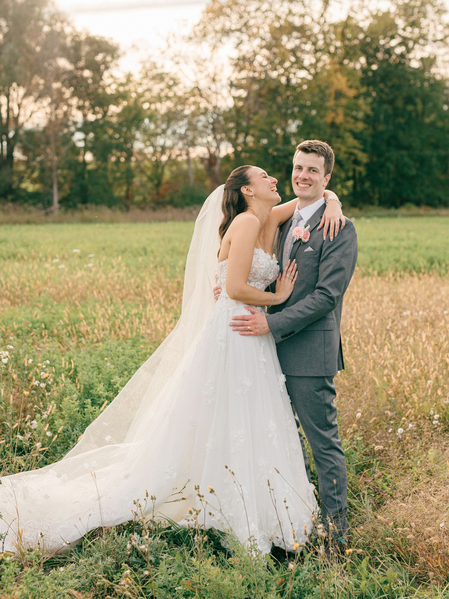 Wedding couple sharing intimate moments in a scenic meadow with trees.