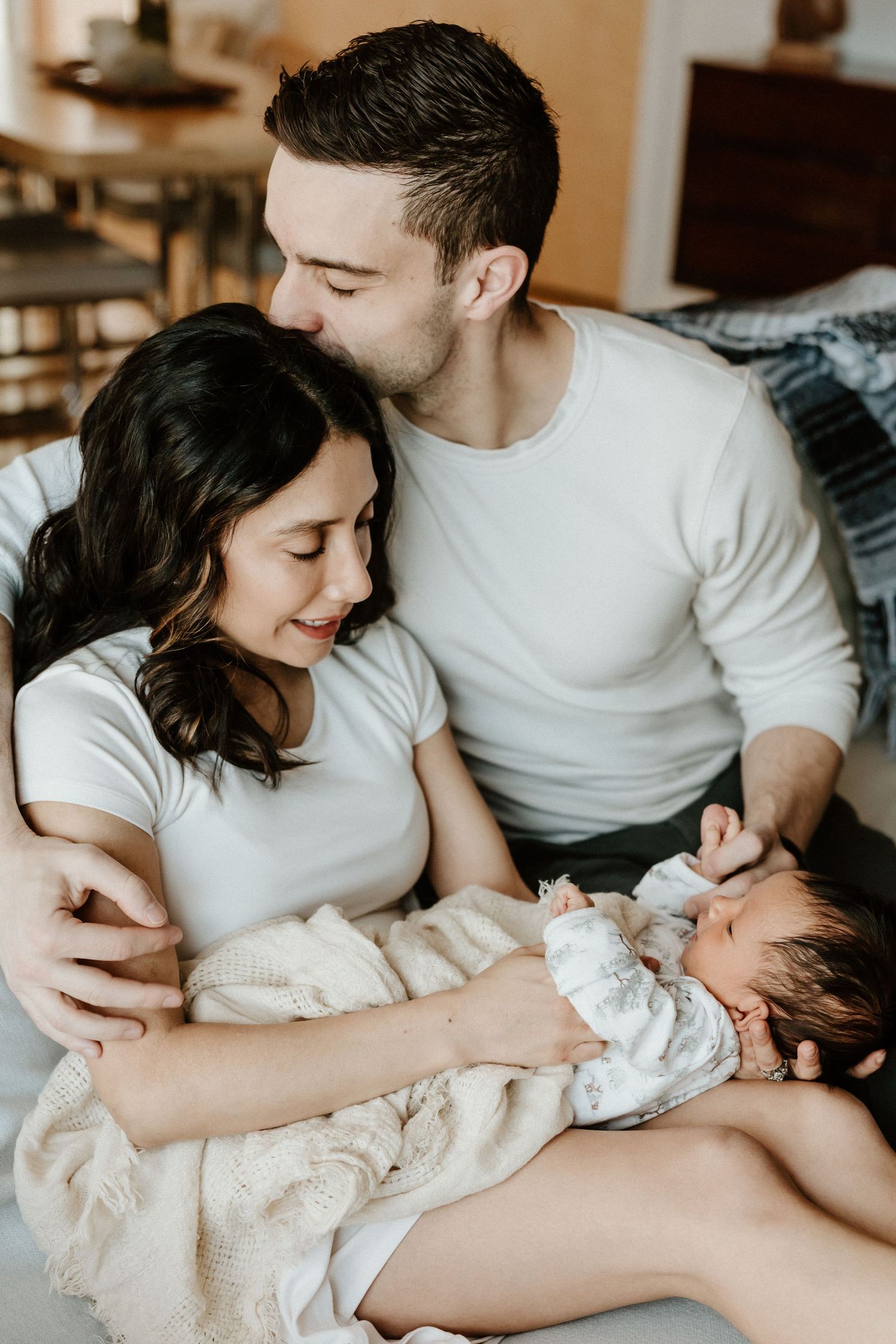 Tender loving moment between new parents with their newborn baby at home.