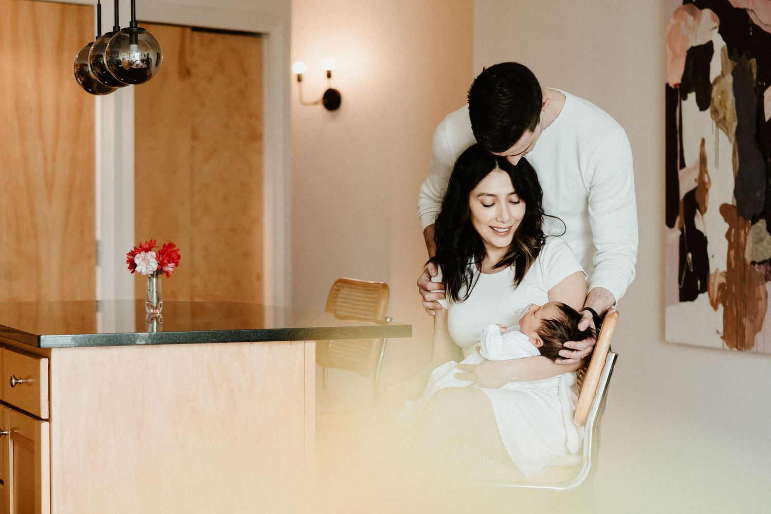 Two people share an intimate moment while laughing together in a bright, modern kitchen setting.