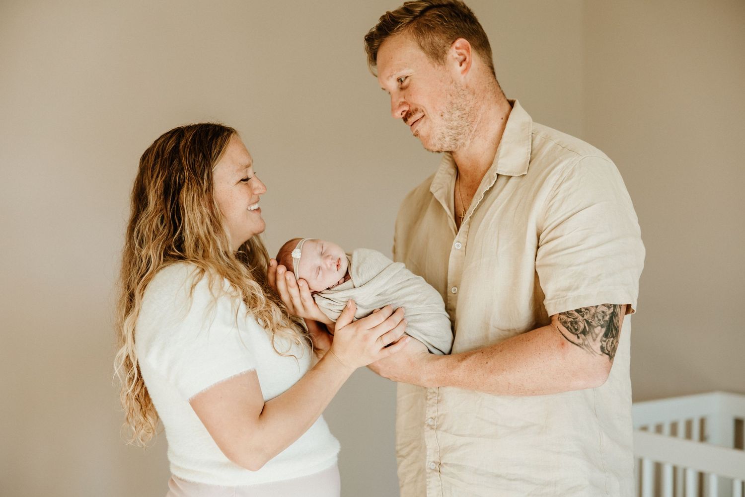 A tender moment shared with a newborn baby in a neutral-toned nursery setting.