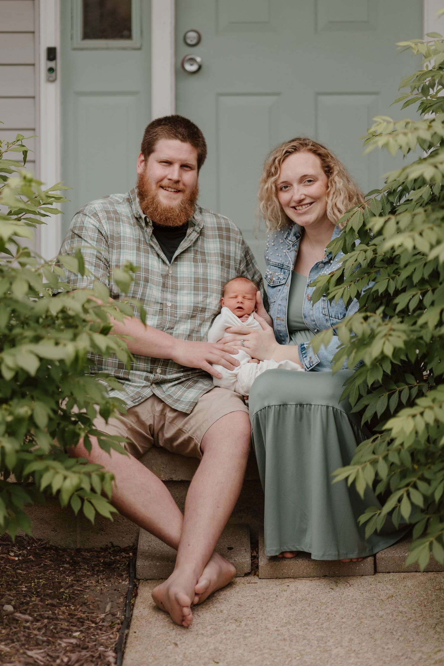 A family sitting together on their front porch steps on a sunny day.
