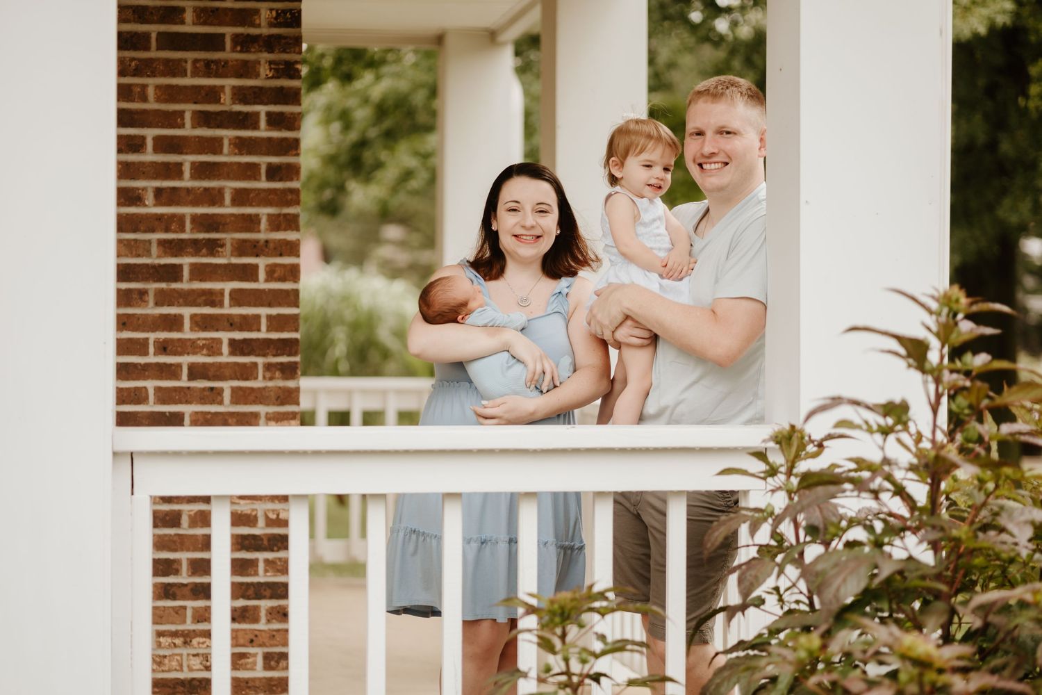 Family enjoying a sunny moment together on their front porch with white columns and brick walls.
