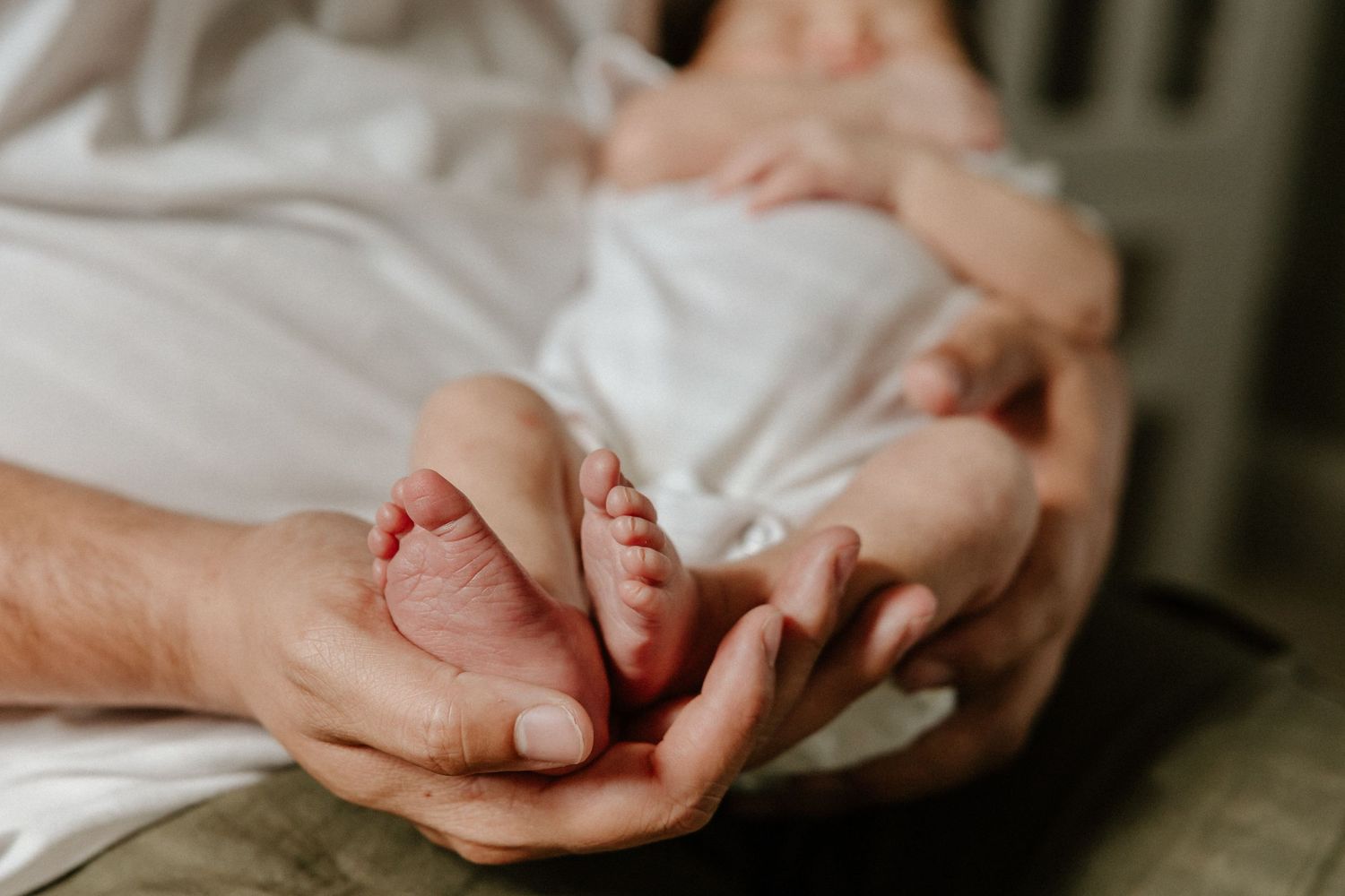 Small baby feet being held tenderly in adult hands.
