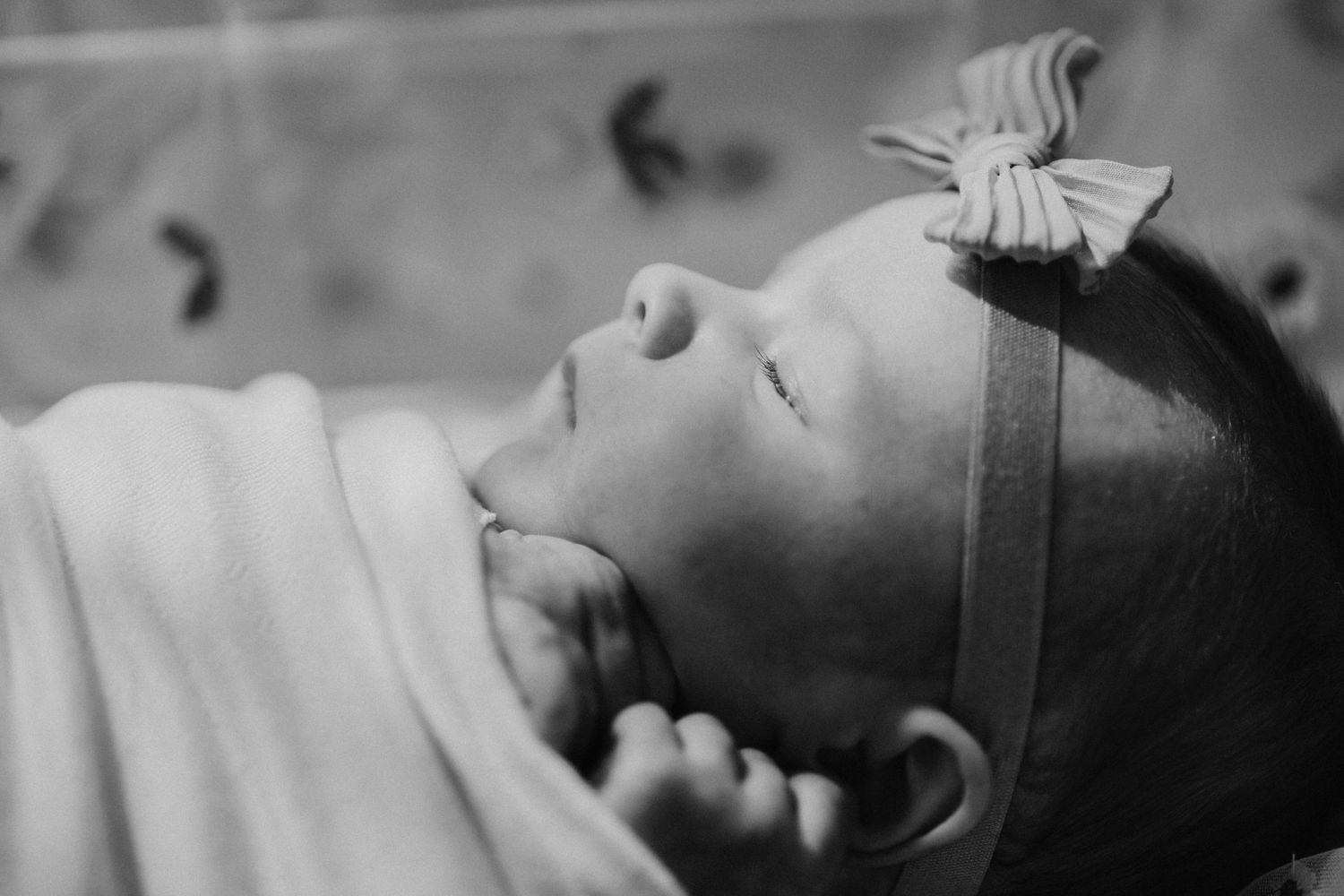 Black and white portrait of sleeping baby with bow headband.