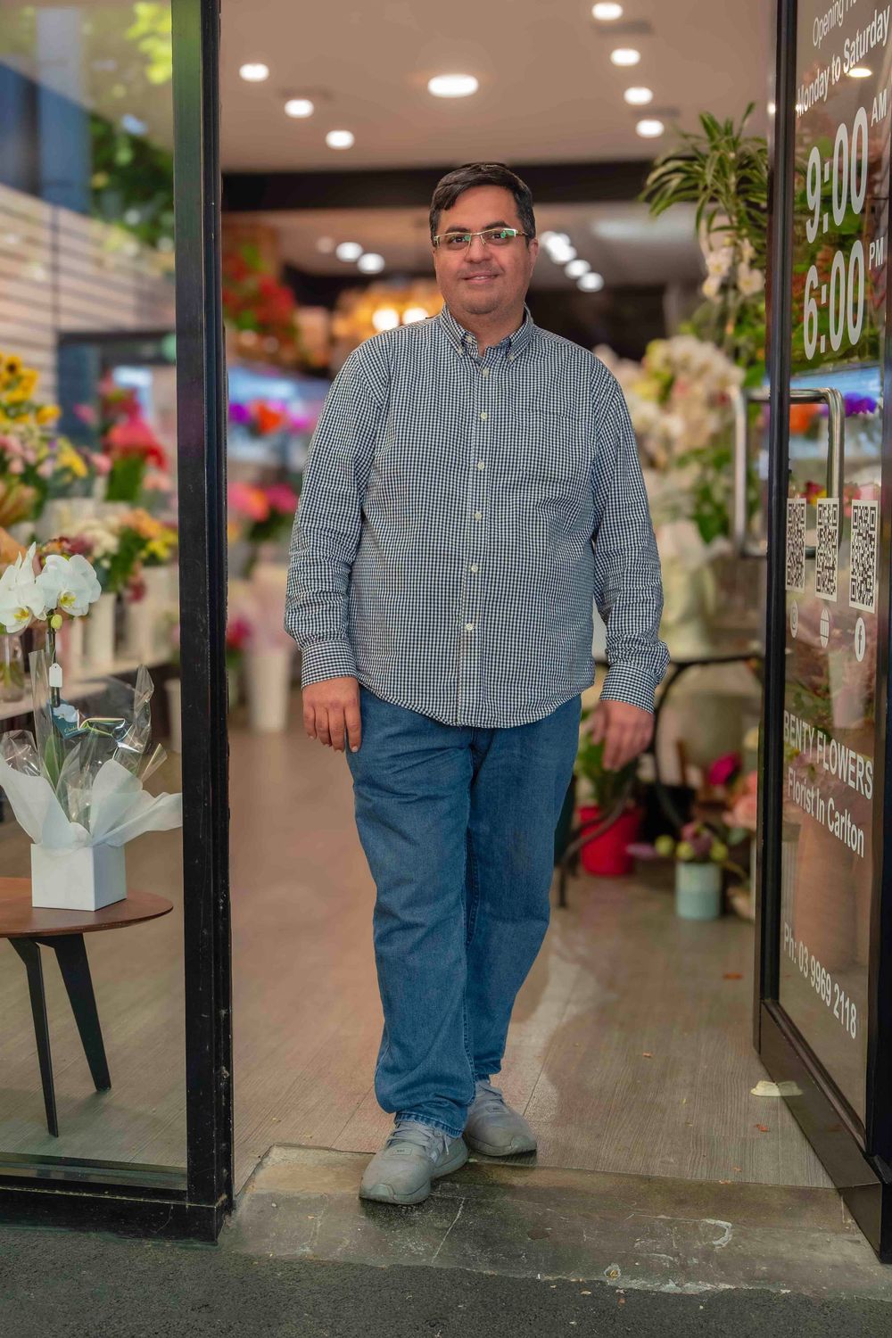 Person in denim and chambray shirt standing in retail store with bright lighting.