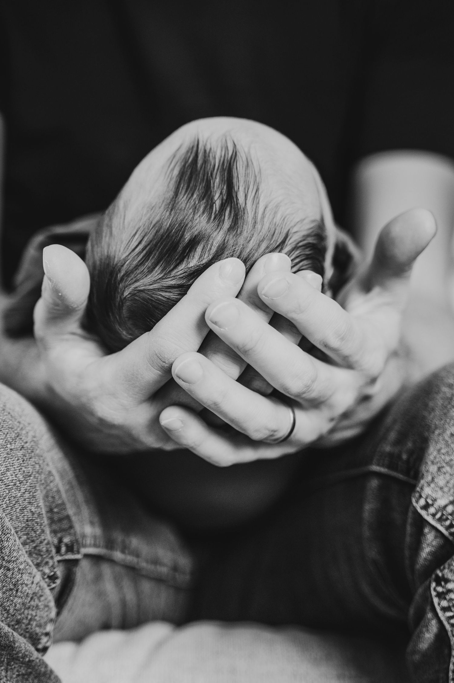Lifestyle newborn photographer captures dad cradling newborns head gently in his hands