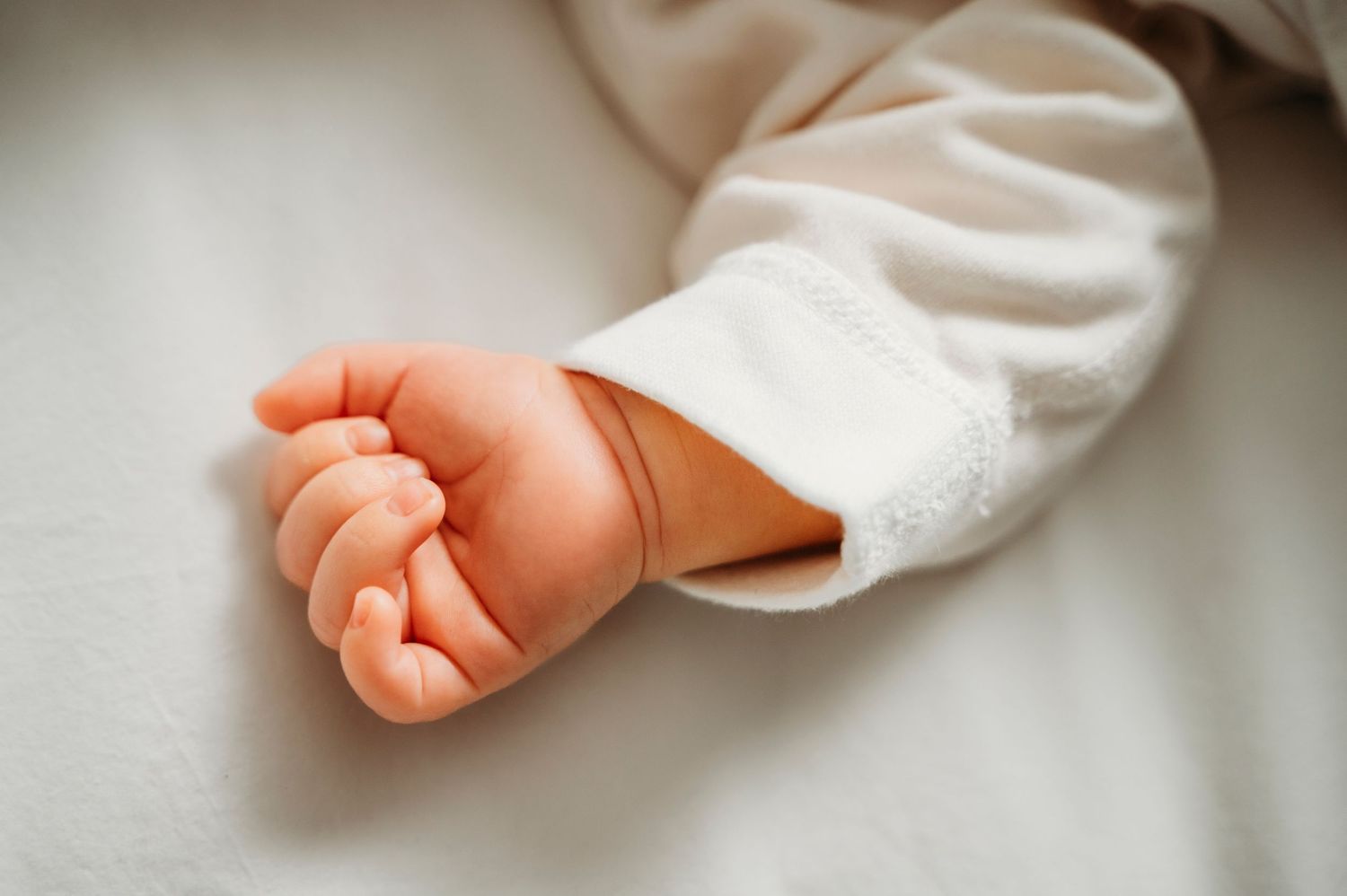 Mississauga lifestyle newborn photographer captures newborn baby's small had on white bed