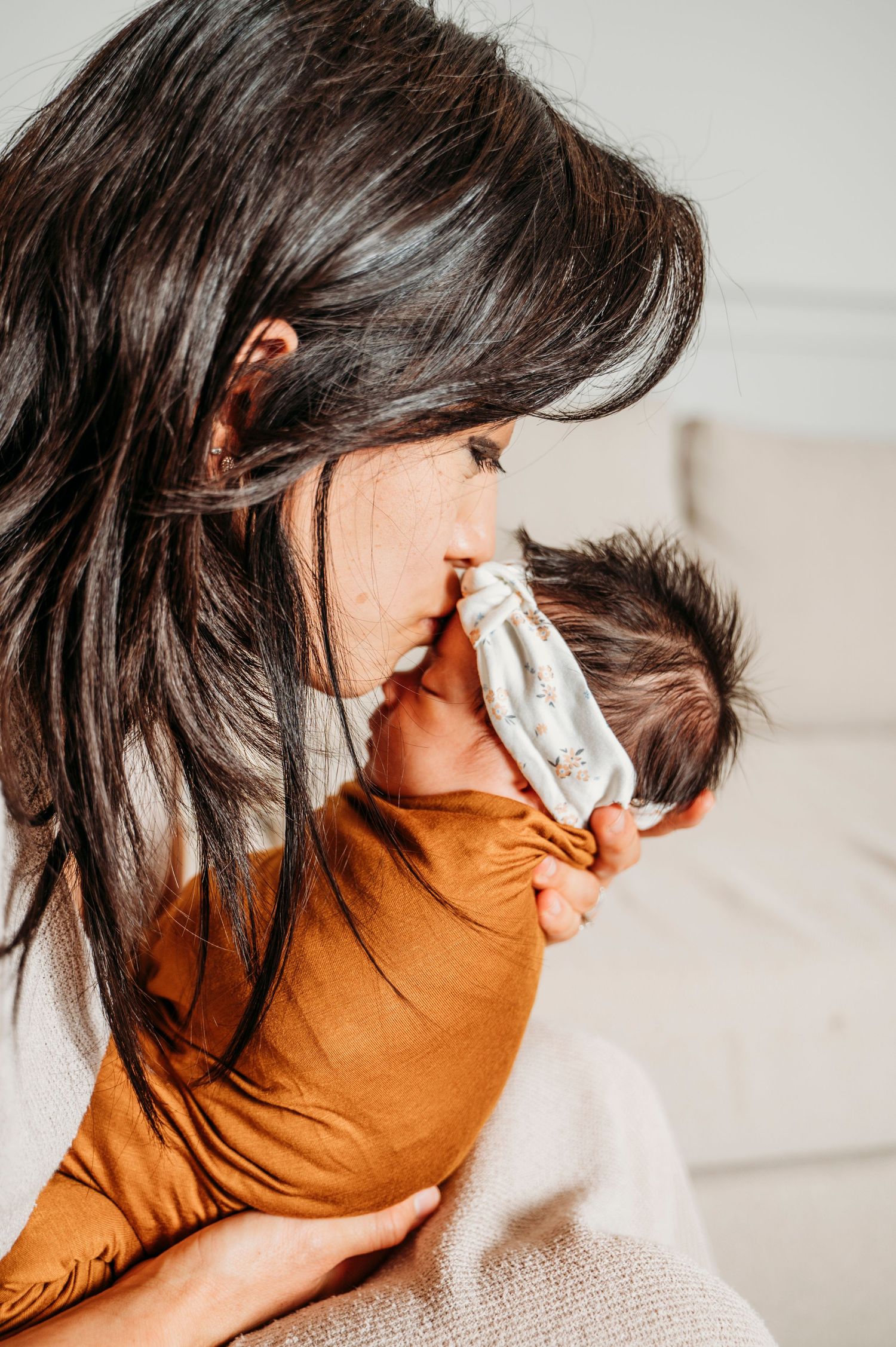 Mother kisses newborn baby on head during lifestyle newborn session