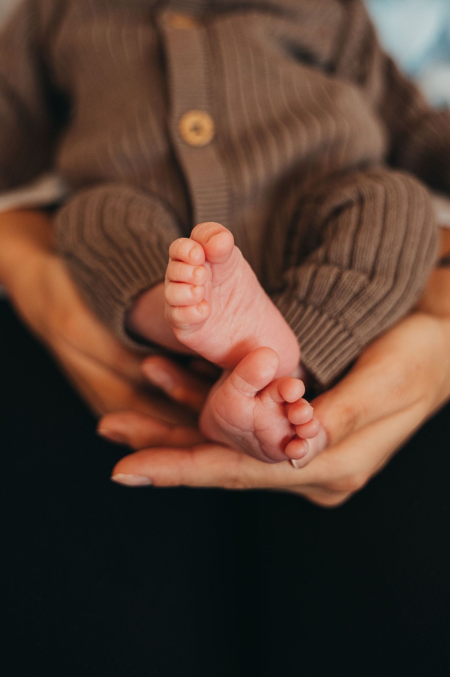 Mother holds newborn baby's feet in their home in Milton
