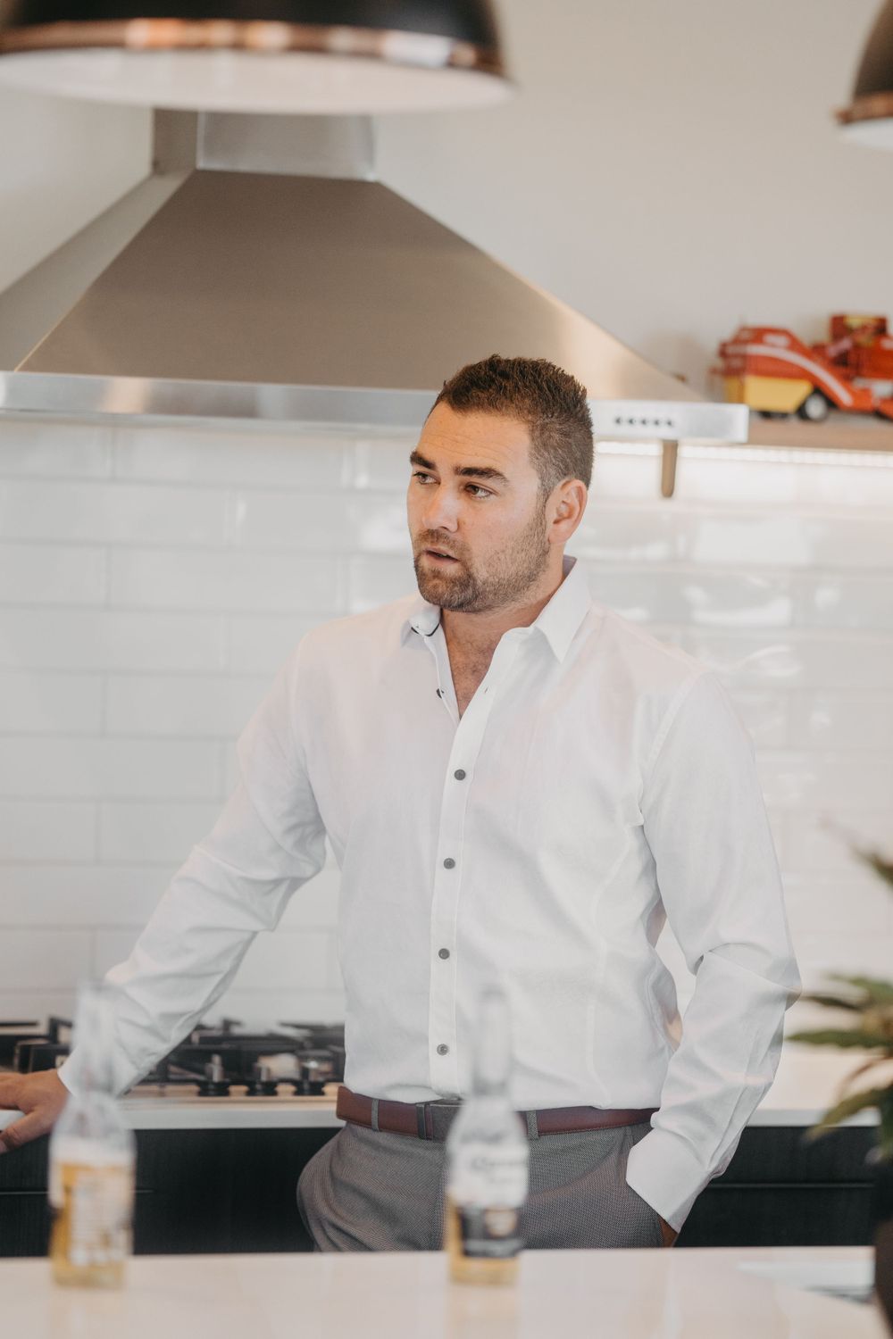 Person in white dress shirt and grey pants standing in modern kitchen setting.