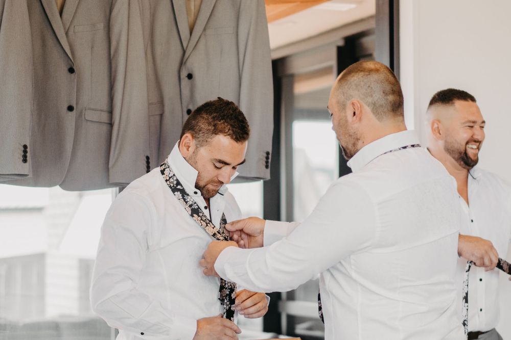 Wedding preparation moment with formal attire visible in background.