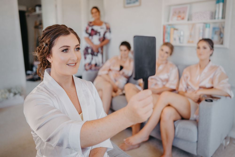 Wedding morning preparations with people in robes looking at phone during getting ready moments.