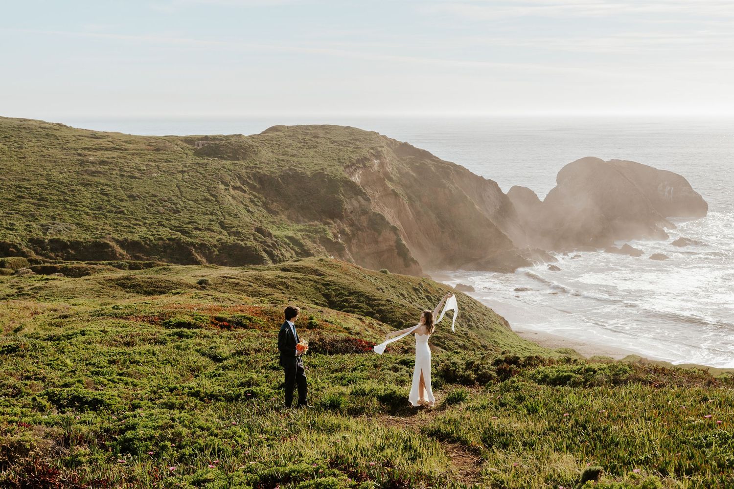 Bride and groom walking past each other on a cliffside field during their San Francisco Bay Area elopement day