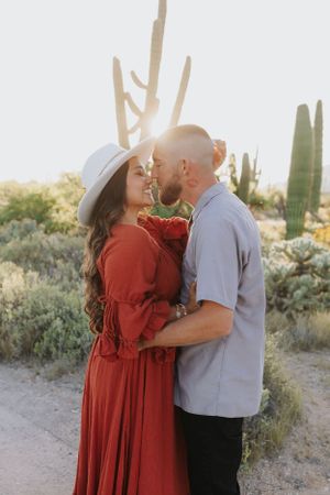An intimate moment between a couple in a desert setting with saguaro cacti at sunset.