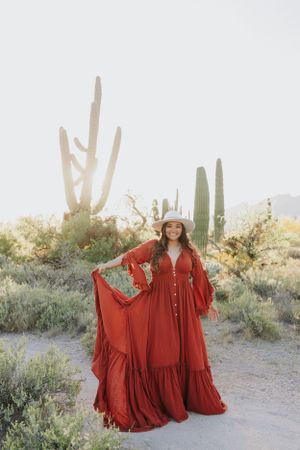 A desert fashion shoot featuring a woman in a red maxi dress among saguaro cacti.