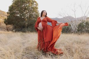 A flowing red dress twirls dramatically against a desert landscape with mountains in the background at sunset.